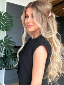 Long glueless wig styled into voluminous waves with half-up section pulled back